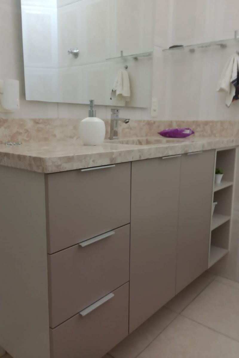 Gabinete de banheiro planejado em MDF cinza com tampo de mármore branco e nichos laterais abertos para toalhas.