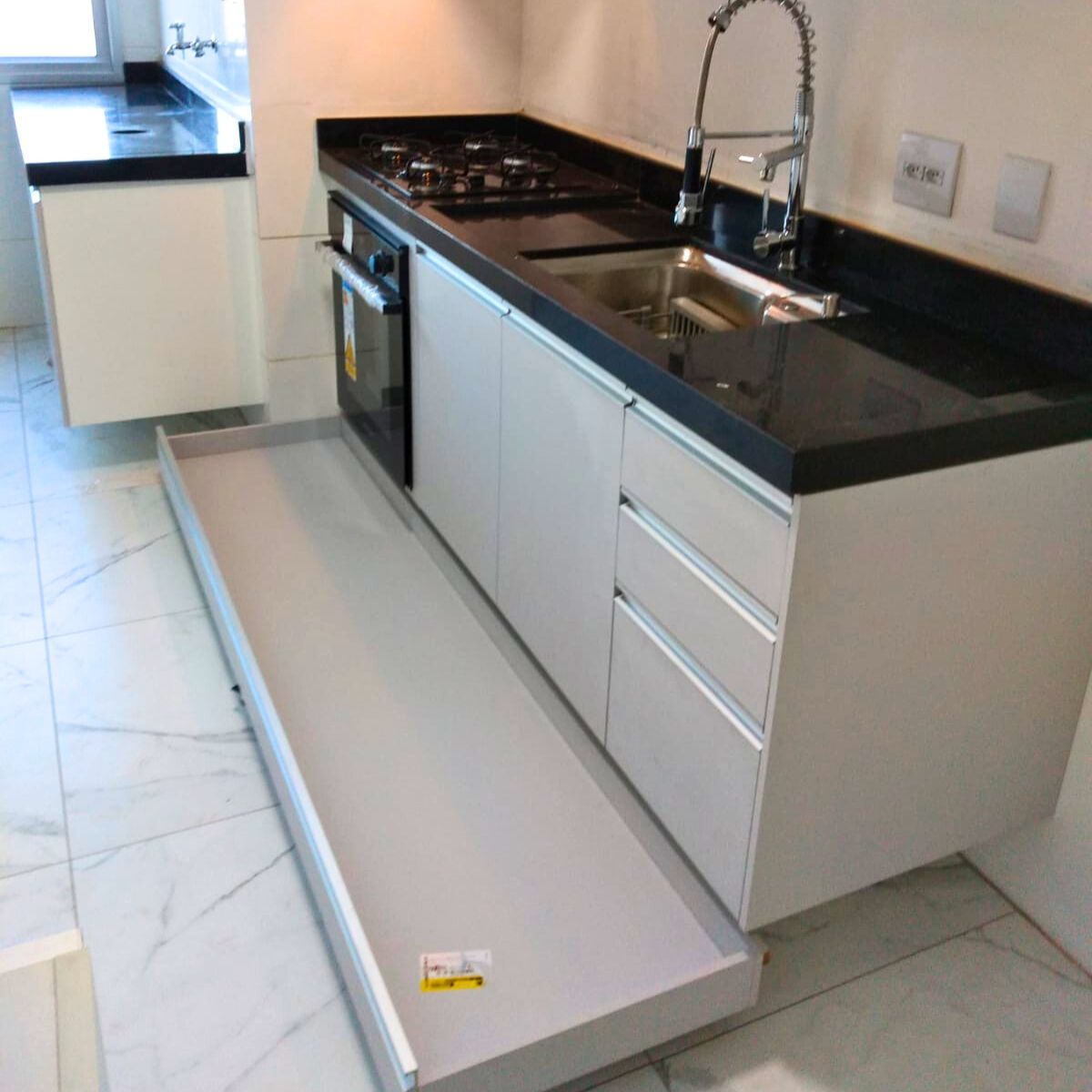 Detalhe de balcão de pia planejado com gavetões espaçosos em MDF claro e acabamento resistente.