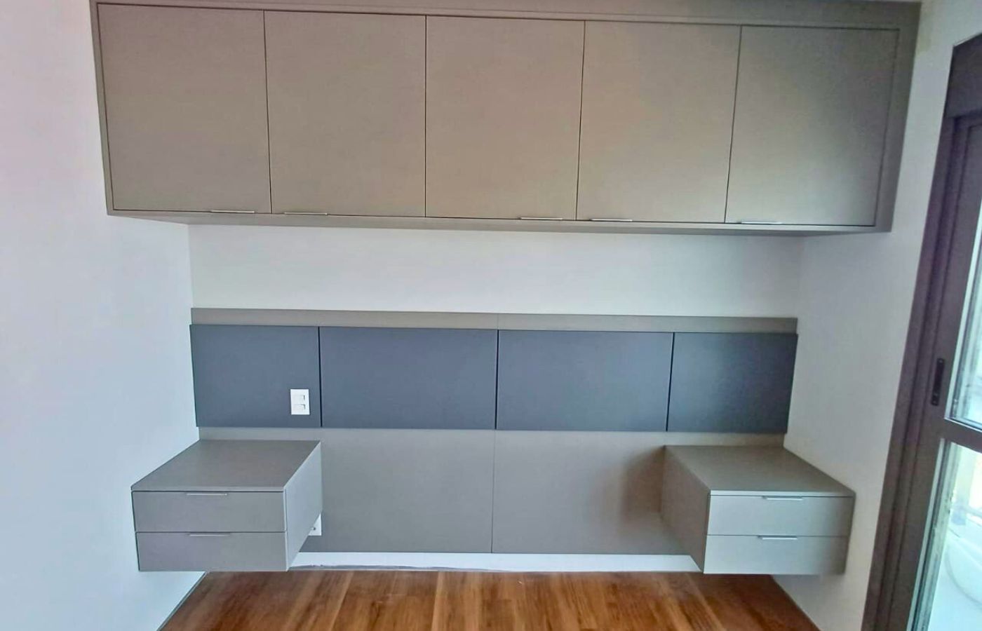 Móveis planejados suspensos em tom cinza e fendi, otimizando o espaço vertical (ideal para quartos ou salas).