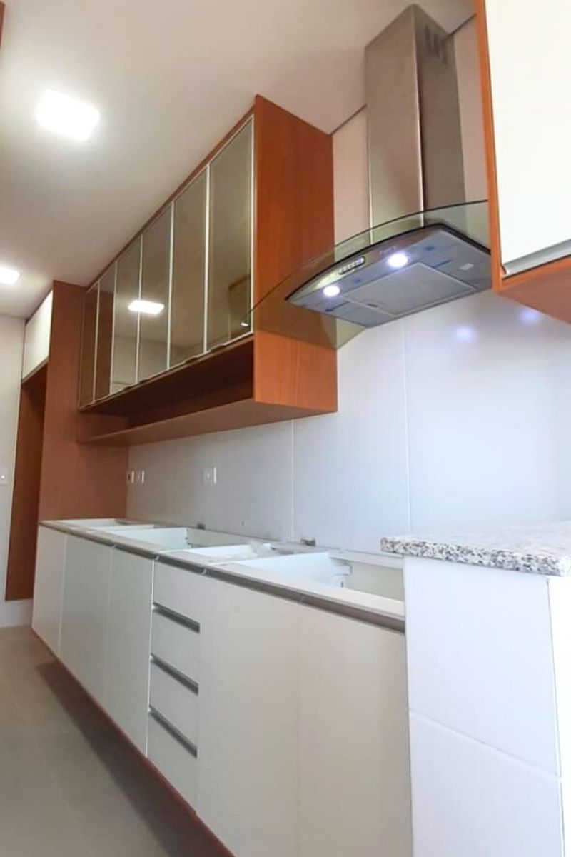 Armários aéreos de cozinha com portas de vidro espelhado e acabamento lateral em madeira, combinando modernidade e aquecimento.