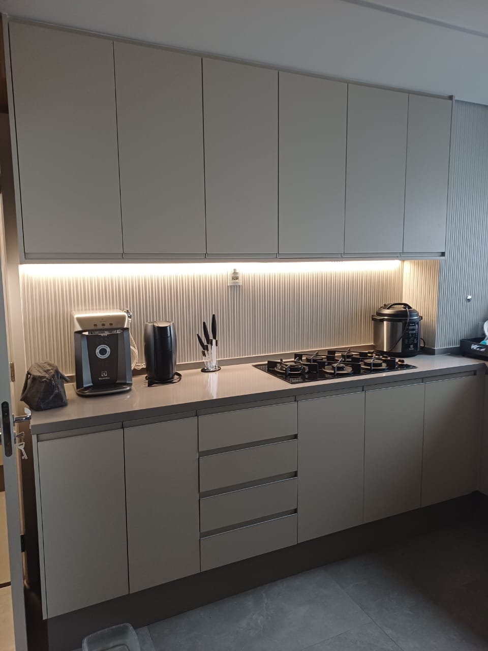 Interior de armário sob medida mostrando o acabamento refinado, iluminação interna funcional e ferragens metálicas modernas.