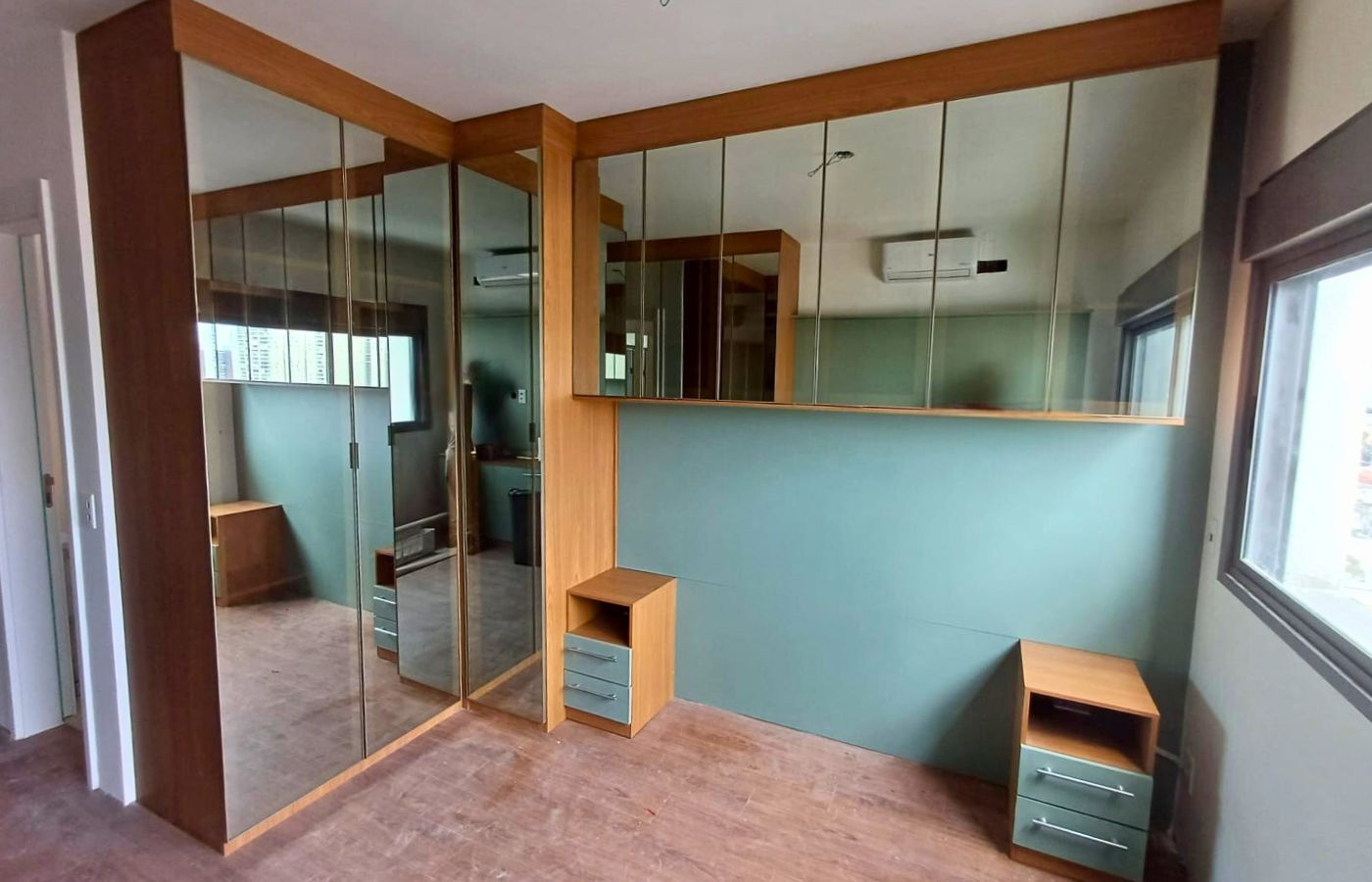 Quarto planejado completo com guarda-roupa de canto com portas de espelho, ampliando visualmente o ambiente.