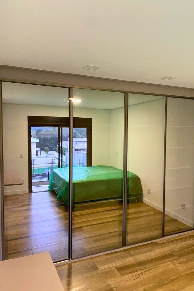 Quarto de casal com guarda-roupa planejado de portas de correr espelhadas, ampliando visualmente o ambiente.