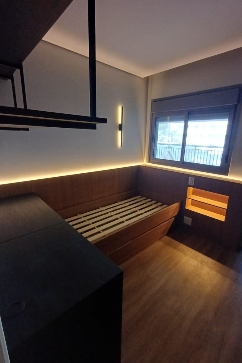 Cama de solteiro planejada com gavetões inferiores e cabeceira moderna com iluminação LED indireta.