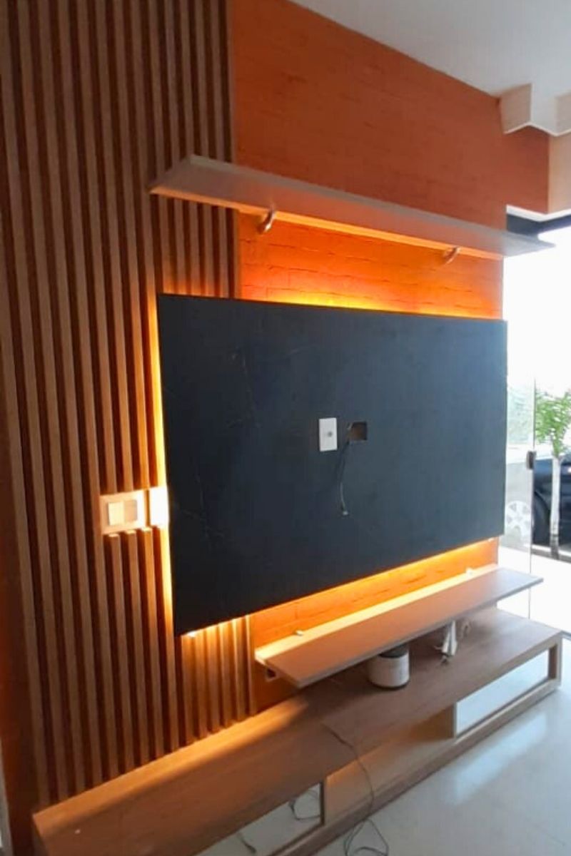 Painel de TV planejado com detalhe ripado e iluminação LED quente, ideal para escritórios ou salas multifuncionais.