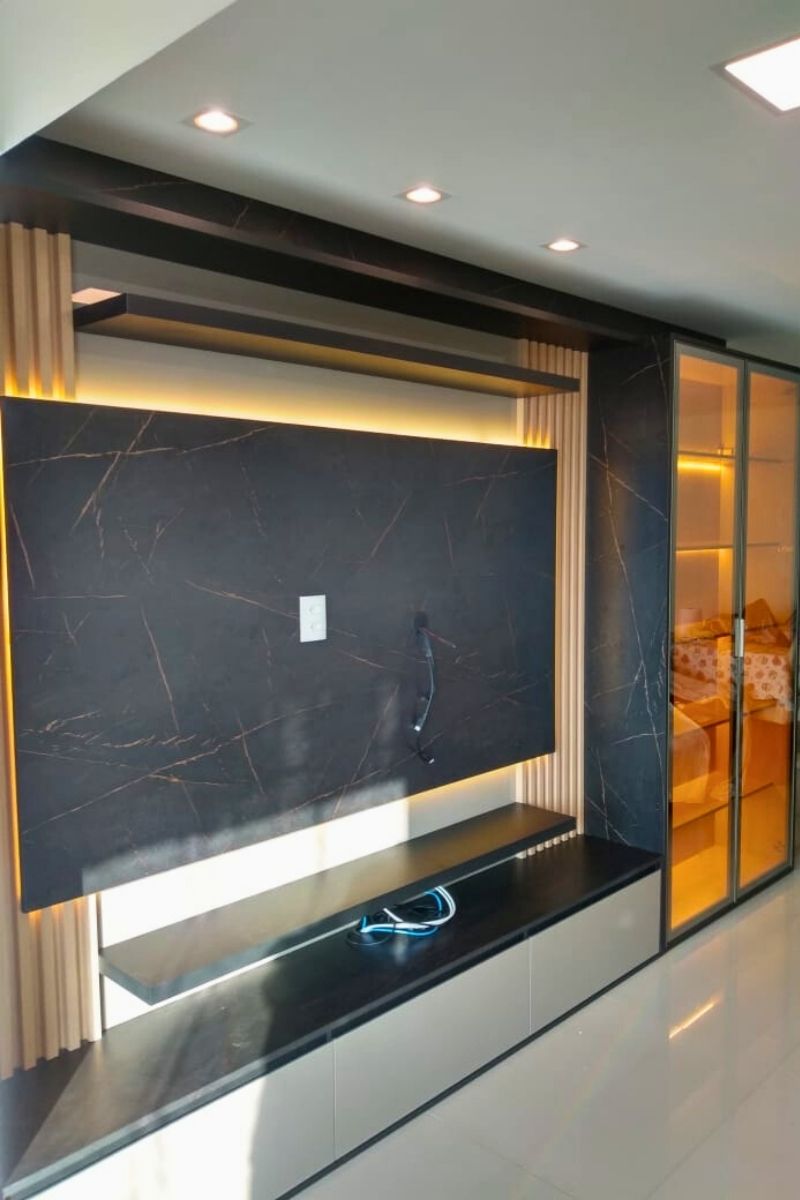 Revestimento de parede para escritório com painel marmorizado escuro e detalhes de iluminação LED vertical.