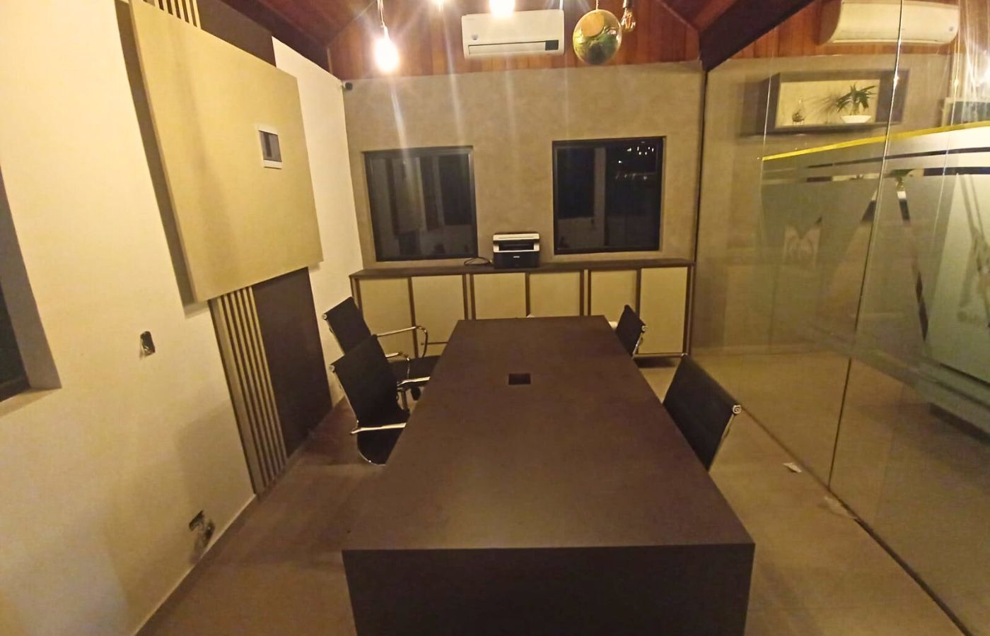 Vista aérea de sala de conferência corporativa com longa mesa de reunião escura e cadeiras confortáveis.