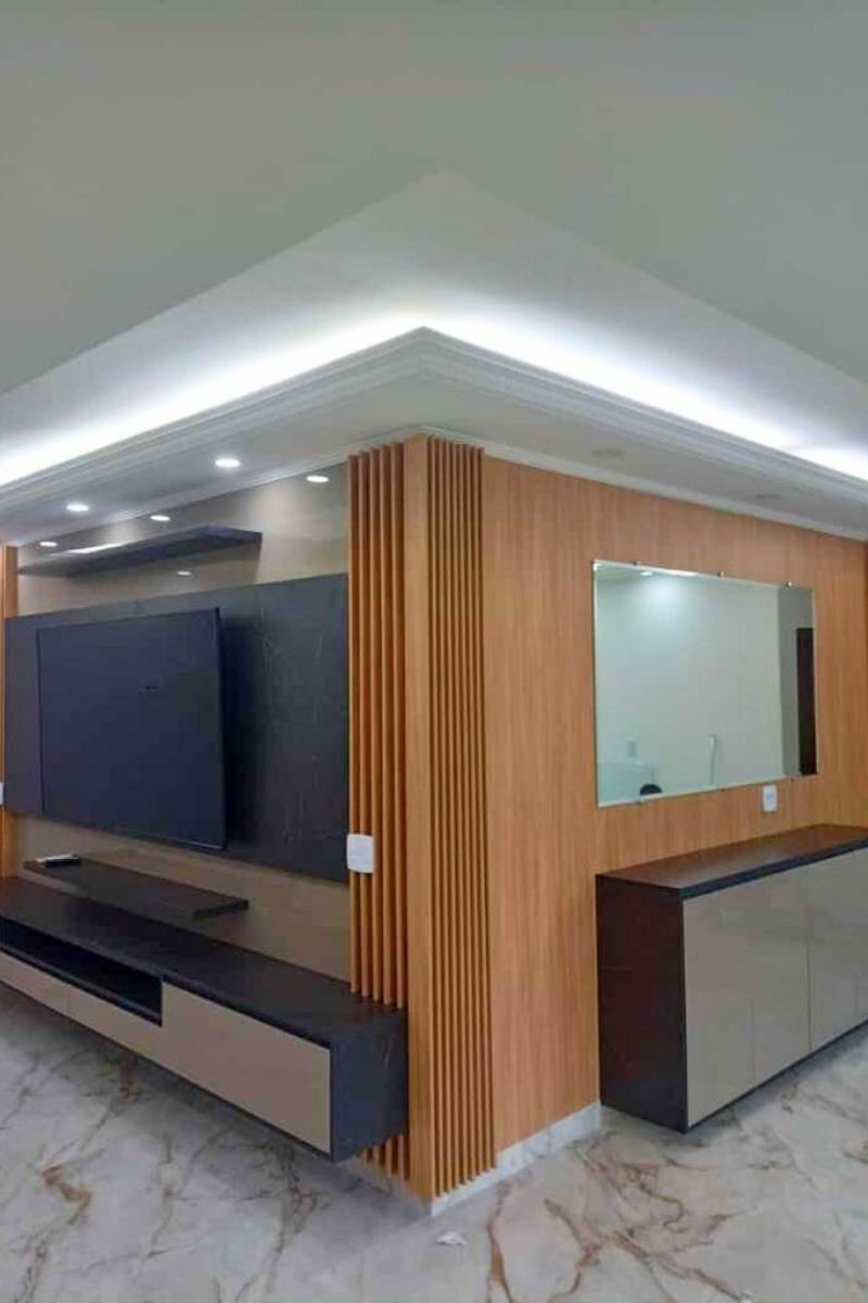 Home theater sofisticado com grande painel ripado de madeira, área central escura para a TV e espelho lateral para amplitude.