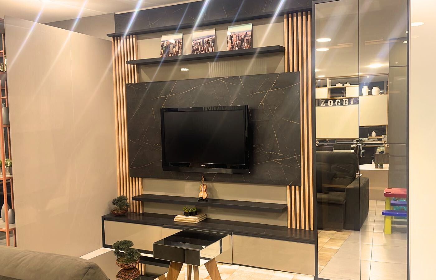 Sala de estar moderna com painel ripado de madeira (TV), espelho central decorativo e sanca de gesso iluminada.