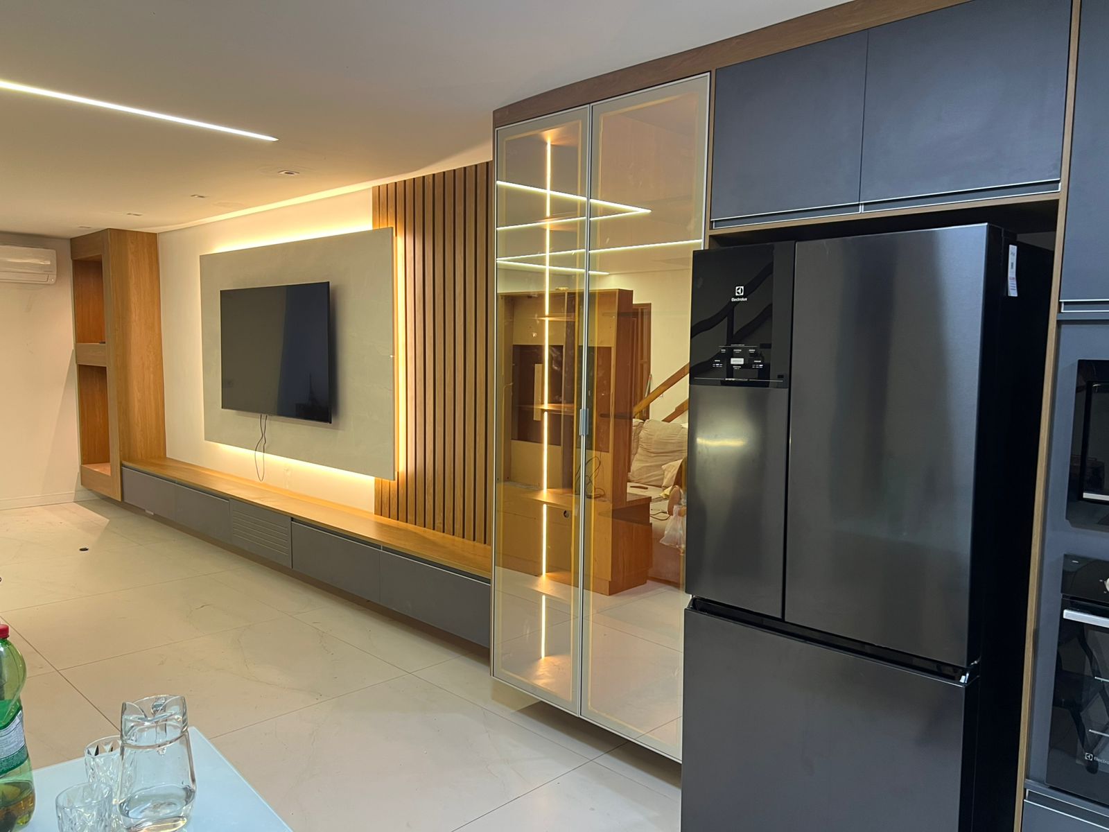 Home office planejado em canto (formato em L) com mesa de madeira e prateleiras brancas suspensas.