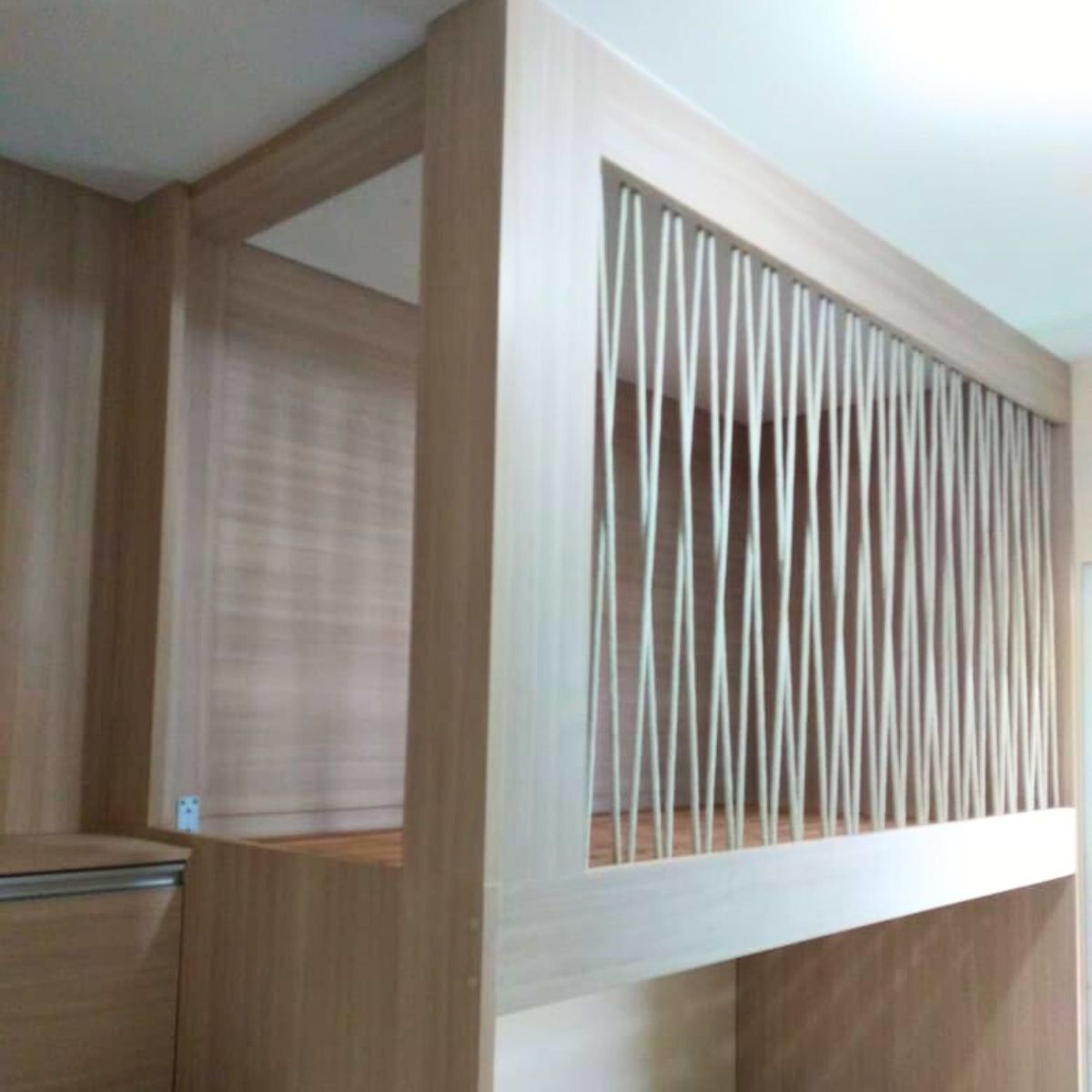 Divisória de ambiente ou cabeceira em madeira ripada clara, parte de projeto de móveis planejados na Zona Leste de SP.