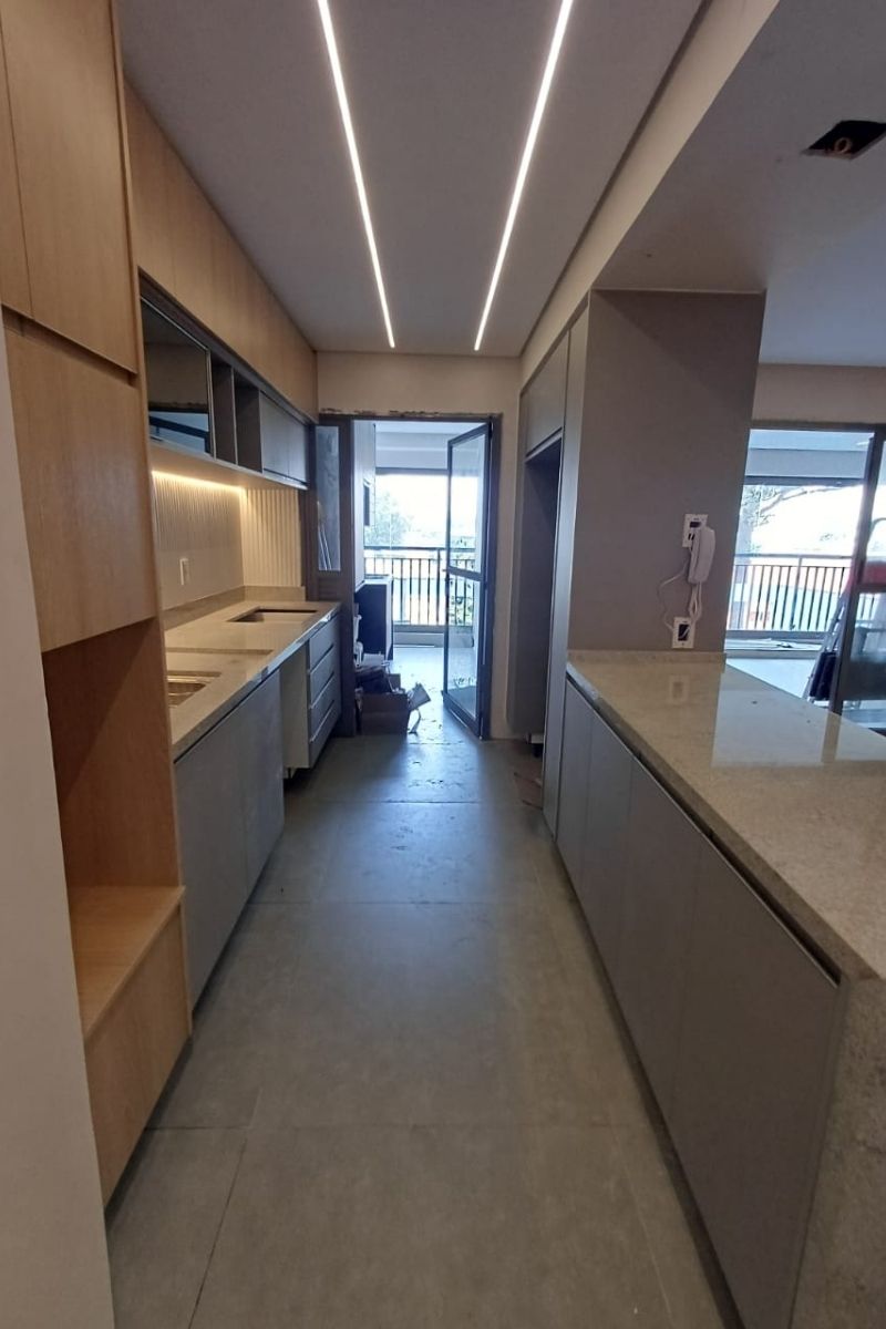 Cozinha de apartamento na Zona Leste com armários planejados em madeira e bancada de granito.