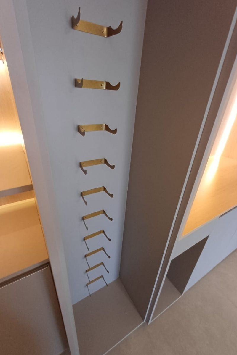 Detalhe interno de closet planejado com sapateira inclinada e iluminação embutida.