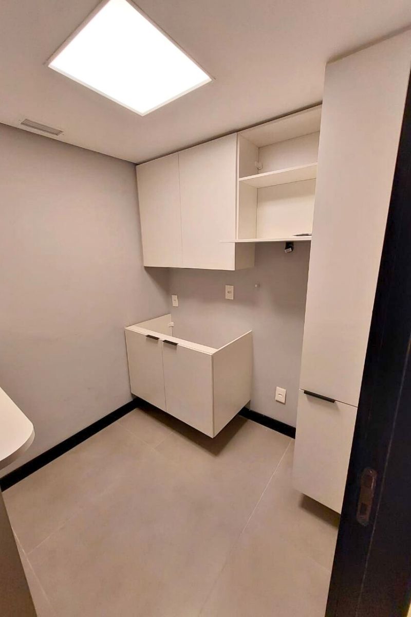 Instalação de armários brancos sob medida para área de serviço ou cozinha compacta.