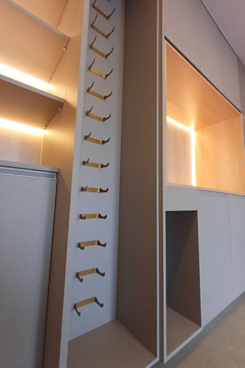 Interior de armário sob medida mostrando o acabamento refinado, iluminação interna funcional e ferragens metálicas modernas.